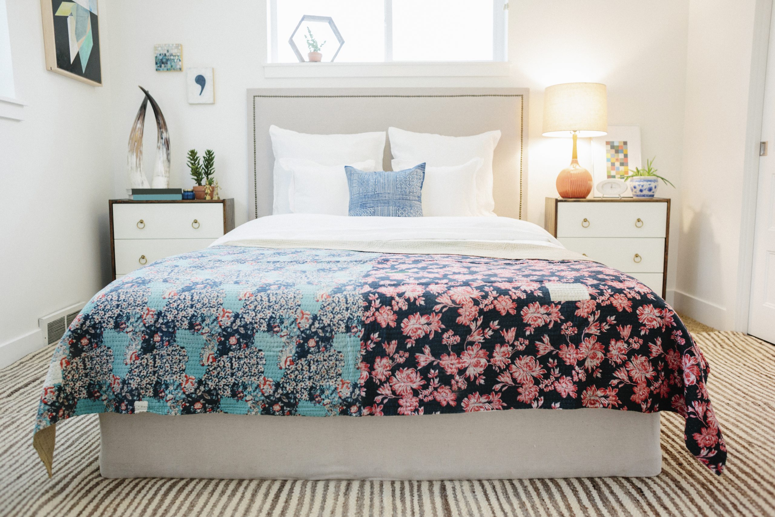 A bedroom in an apartment with a double bed covered with a patched quilt with patchwork and floral patterns. Retro look.